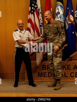 Le Lgén de l'Armée de terre (Dr) Ronald place, directeur de l'Agence de santé de la Défense, félicite le Lgén de la Force aérienne, le colonel Robert Krell, membre du personnel en oncologie chirurgicale, pour avoir reçu le Prix de la bourse d'études en action du 2nd trimestre FY22 lors de la Journée de recherche du Consortium d'éducation sanitaire des services en uniforme de San Antonio, au Centre médical de l'Armée de Brooke, à la base conjointe Texas, 28 avril 2022. Le document de recherche de Krell intitulé « traitement néoadjuvant de l’adénocarcinome du canal pancréatique : analyse par rapport à la propension des complications postopératoires à l’aide de l’ACS-NSQIP » a été publié dans les Annales de l’oncologie chirurgicale. Banque D'Images