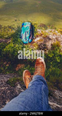 Sac à dos et jambes de randonnée dans les chaussures de sport de la jeune femme se reposant dans une randonnée en montagne dans la vallée Banque D'Images