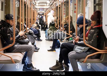 Moscou, Russie - janvier 2023 : personnes dans un métro en hiver, les passagers sont assis avec un smartphone. Intérieur de la voiture de métro moderne Banque D'Images