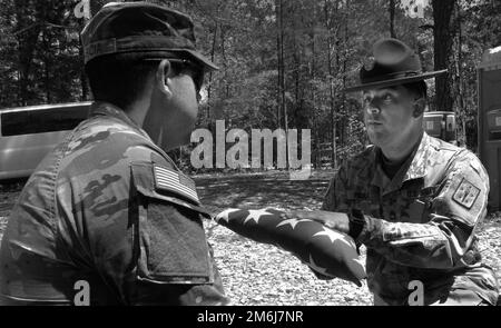 Le Sgt. 1st classe Waldemar Paoli IV de la Compagnie Delta, 832nd Bataillon d'artillerie, présente un drapeau américain plié à un membre du service pendant une séance de pratique de détail des honneurs funéraires 28 avril à la zone d'entraînement 23. Le détail effectue généralement 30-45 funérailles et événements commémoratifs chaque mois. Banque D'Images