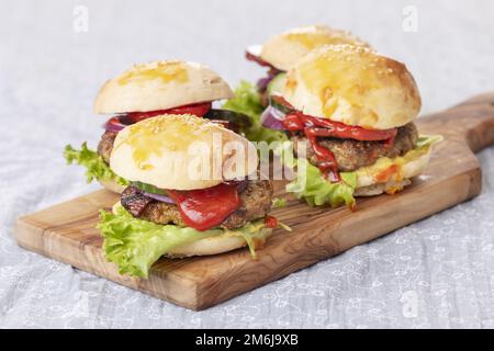 Quatre petits hamburgers sur une planche Banque D'Images