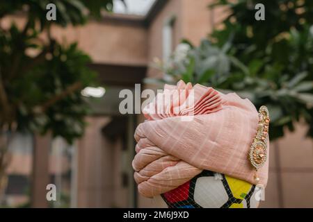 Une balle de football colorée avec une safa indienne rose sur elle sur un fond flou Banque D'Images
