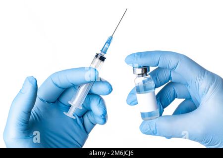 Mains en gants bleus tenant un flacon de vaccin et une seringue Banque D'Images