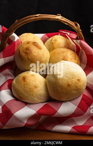 Une photo en gros plan d'un petit panier avec une serviette rouge et blanche de petits pains faits maison cuits au four. Banque D'Images