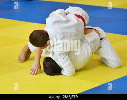 Deux garçons judoka dans kimono concourent sur le tatami Banque D'Images