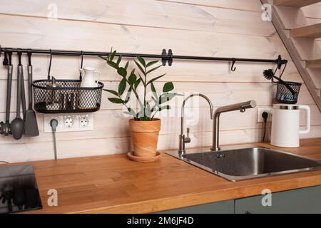 Ustensiles de cuisine en laiton, accessoires de chef. Cuisine suspendue avec mur de carreaux blancs et plan d'examen en bois.plante verte sur le backgro de cuisine Banque D'Images