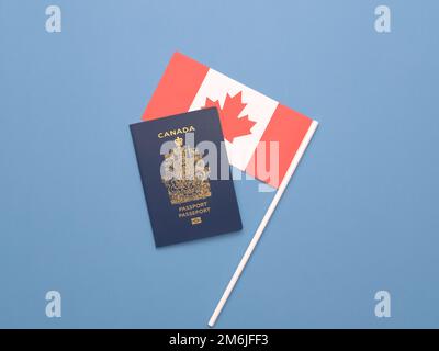 Un passeport canadien sur un drapeau canadien sur un fond bleu clair et solide Banque D'Images