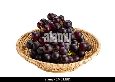 Bouquet de raisins violets mûrs dans un panier de bambou isolé sur fond blanc. Banque D'Images