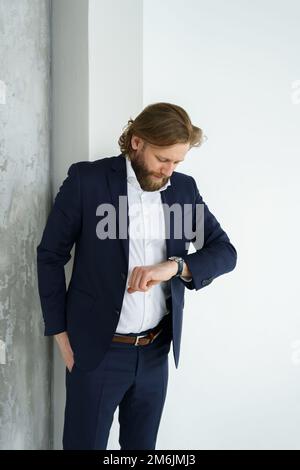 Un bel homme brutal barbu et aux cheveux longs, un homme d'affaires élégant sur fond blanc Banque D'Images