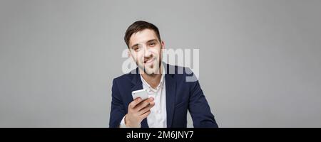 Concept d'affaires - Portrait beau heureux beau homme d'affaires en costume jouer à la moblie téléphone et sourire avec ordinateur portable au travail de Banque D'Images