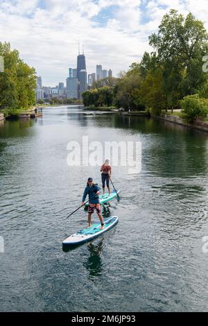 Homme et femme paddleboard dans la rivière avec la ville en arrière-plan Banque D'Images