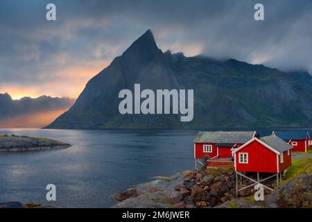 Coucher de soleil incroyable à travers la brume et le Mont Reinebringen sur les maisons rouges de Hamnoy, îles Lofoten, Norvège Banque D'Images