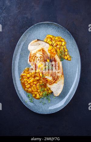 Steak d'espadon frit avec chutney de mangue et herbes servi comme vue de dessus sur une assiette design Banque D'Images