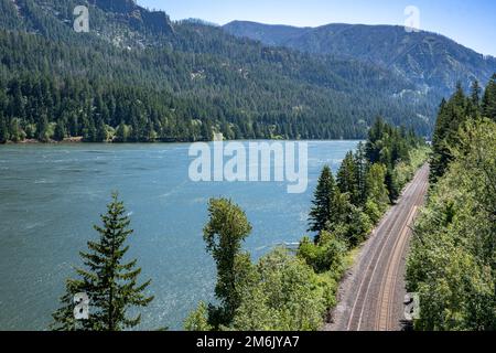 Paysage d'été pittoresque avec un sentier de chemin de fer de montagne sinueux qui longe la rive de la rivière Columbia dans la gorge de Columbia, permettant le transport de commer Banque D'Images