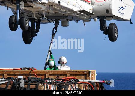 MER DES PHILIPPINES (28 avril 2022) Spécialiste en logistique le marin Cameron Mudgett, à gauche, de Carlsbad, en Californie, et le spécialiste en logistique en chef Willie Bates, d'Elizabethtown, en Ky., placez un crochet de chargement sur un Super Puma AS332 sur le pont de vol du porte-avions de la classe Nimitz USS Abraham Lincoln (CVN 72) Au cours d'une reconstitution verticale en mer avec le navire de fret et de munitions du Commandement militaire maritime USNS Cesar Chavez (T-AKE 14). Abraham Lincoln Strike Group est en cours de déploiement prévu dans la zone d'exploitation de la flotte américaine 7th afin d'améliorer l'interopérabilité par le biais d'alliances et de partenariats W Banque D'Images