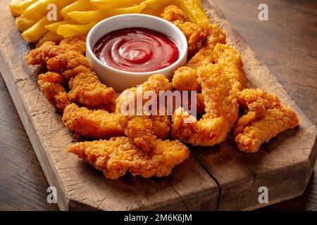 Quartiers de poulet battus, nuggets croustillants, avec une sauce barbecue sur une table en bois Banque D'Images