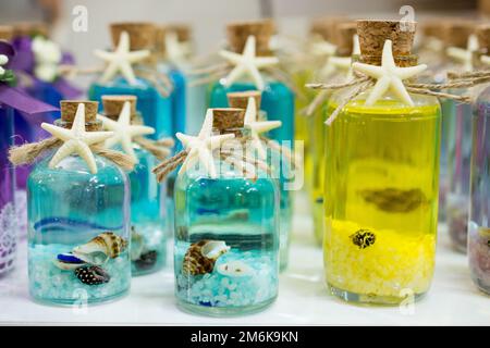 Jeu de petites bouteilles transparentes vides remplies de cailloux et de coquillages Banque D'Images