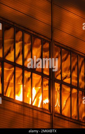 La façade en verre et en fer d'un énorme gratte-ciel au coucher du soleil, acier, couleur orange, reflet du soleil Banque D'Images