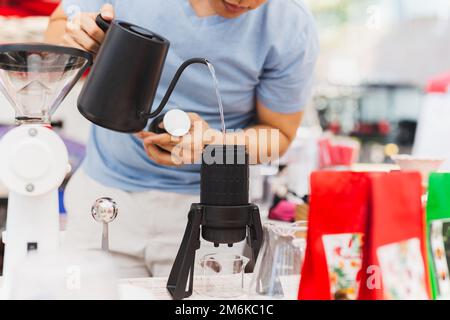 Le barista verse de l'eau chaude dans l'aérateur de café du café. Banque D'Images