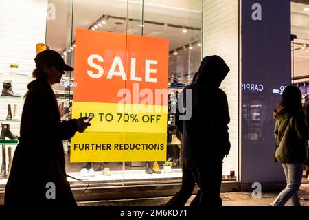 Londres, Royaume-Uni. 04th janvier 2023. Les clients se promèneront devant un panneau de vente sur Oxford Street dans le centre de Londres. L'escalade continue de la crise du coût de la vie signifie que la récession britannique peut durer plus longtemps que prévu. Crédit : SOPA Images Limited/Alamy Live News Banque D'Images