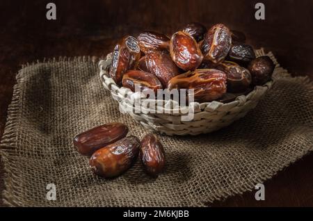 Dates mûres dans un panier sur fond de bois sombre Banque D'Images