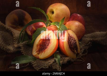 Nectarines sur un tissu épais sur un fond en bois sombre dans un style rustique Banque D'Images