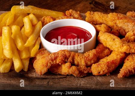 Filets de poulet, panés et frits, avec une sauce rouge et des frites Banque D'Images