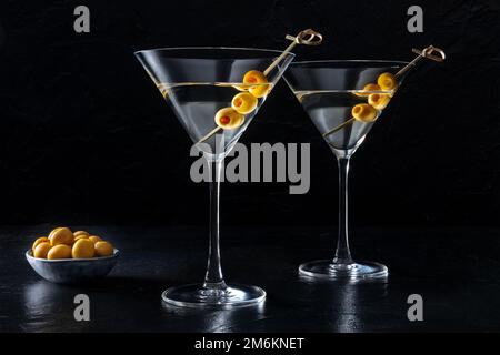 Martini, deux verres aux olives épicées, sur fond sombre Banque D'Images