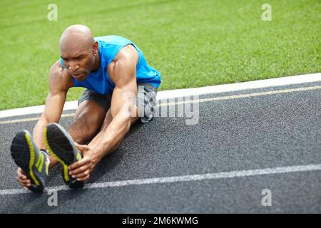 Vous devez vous mettre en place avant la course. Prise de vue en longueur d'un athlète masculin qui étire ses muscles sur la piste de course. Banque D'Images