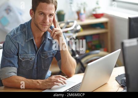 Travailler dur sur des concepts commerciaux créatifs. Un jeune homme travaillant sur son ordinateur portable au bureau. Banque D'Images