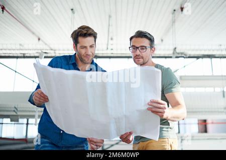 Examiner les plans pour détecter les défauts éventuels. deux architectes qui examinent ensemble les plans. Banque D'Images