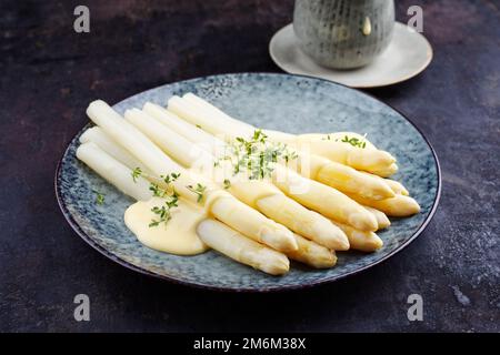 Asperges traditionnelles blanches vapeur de style moderne avec sauce au beurre hollandaise et cresson servies en gros plan sur un dessin nordique p Banque D'Images