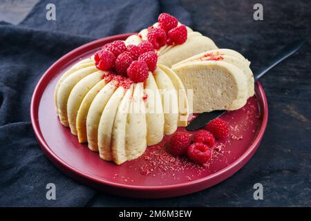 Gâteau traditionnel italien à la vanille accompagné de framboises fraîches servi en gros plan sur une assiette à motif rouge Banque D'Images