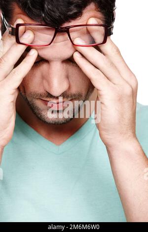 Ma tête est sur le point d'exploser. Un jeune homme frottant son front contre le stress tout en étant isolé sur un fond blanc. Banque D'Images