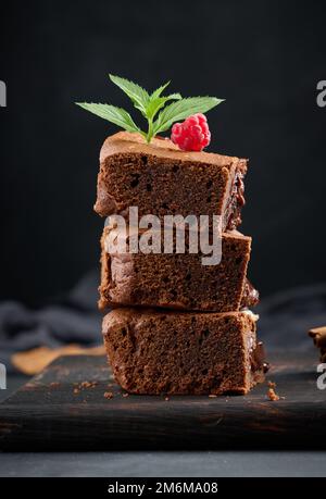 Morceaux de tarte au chocolat au brownie sur table noire, délicieux dessert Banque D'Images