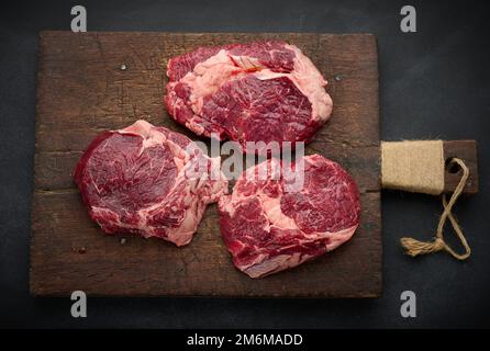 Le filet de bœuf cru se trouve sur une planche à découper sur une table noire, vue de dessus Banque D'Images