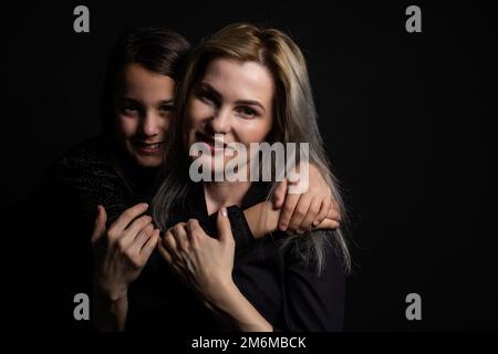 une petite fille avec sa mère prie tout en embrassant Banque D'Images