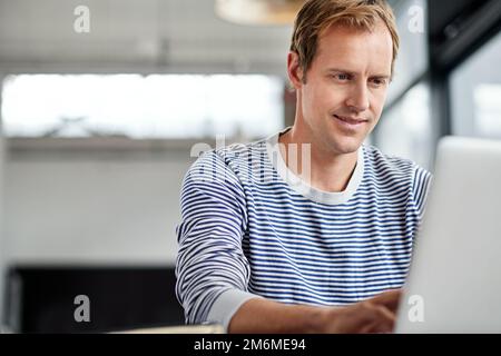 Internet fait partie intégrante de sa journée. un homme travaillant sur un ordinateur portable dans un bureau. Banque D'Images