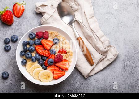 Porridge de flocons d'avoine avec fruits et baies sur table rustique en pierre Banque D'Images