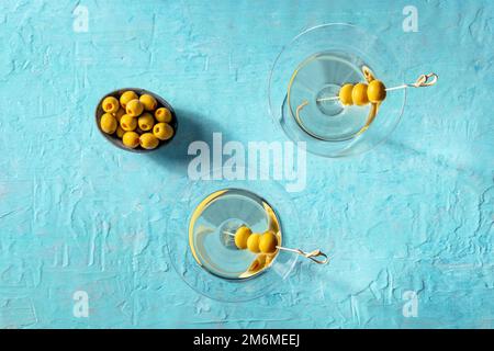 Martini, deux verres aux olives épicées, sur fond bleu Banque D'Images