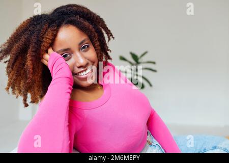 Fille millénaire afro-américaine, vêtue de rose, satisfaite et calme Banque D'Images