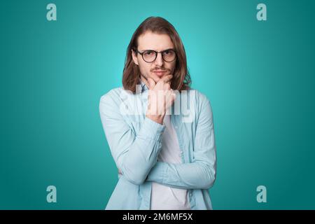 Portrait en gros plan d'un homme sérieux et concentré qui pense tout en touchant le menton isolé sur fond vert. Portrait isolé. Concept créatif Banque D'Images