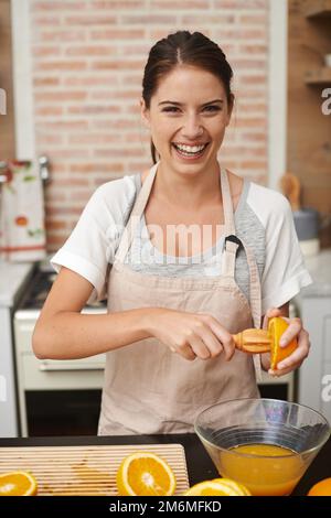 Obtenir sa dose quotidienne de vitamine C. Portrait d'une femme attrayante préparant du jus d'orange frais dans la cuisine. Banque D'Images