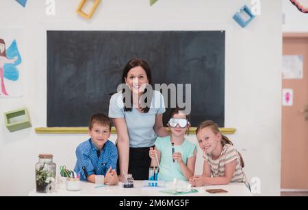 École élémentaire de sciences en classe: Un professeur enthousiaste explique la chimie à divers groupes d'enfants, Little Boy Mixes Chem Banque D'Images