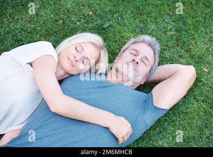 Contentement dans un pré. Un couple mature qui dormait ensemble sur l'herbe. Banque D'Images