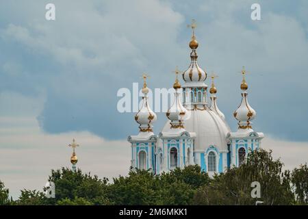 Dômes d'or et croix de la cathédrale de Smolny par temps ensoleillé sur fond de ciel sombre Banque D'Images