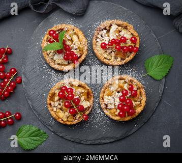 Tarte aux fruits avec des raisins rouges saupoudrés de sucre sur une table noire Banque D'Images