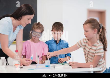 École élémentaire de sciences en classe: Un professeur enthousiaste explique la chimie à divers groupes d'enfants, Little Boy Mixes Chem Banque D'Images