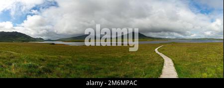 Paysage panoramique du sentier côtier de Claggan Mountain tourbière et promenade avec la chaîne de montagnes Nephir en arrière-plan Banque D'Images