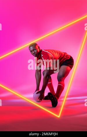 Un joueur afro-américain avec un ballon de rugby plié par un triangle lumineux sur fond rose Banque D'Images